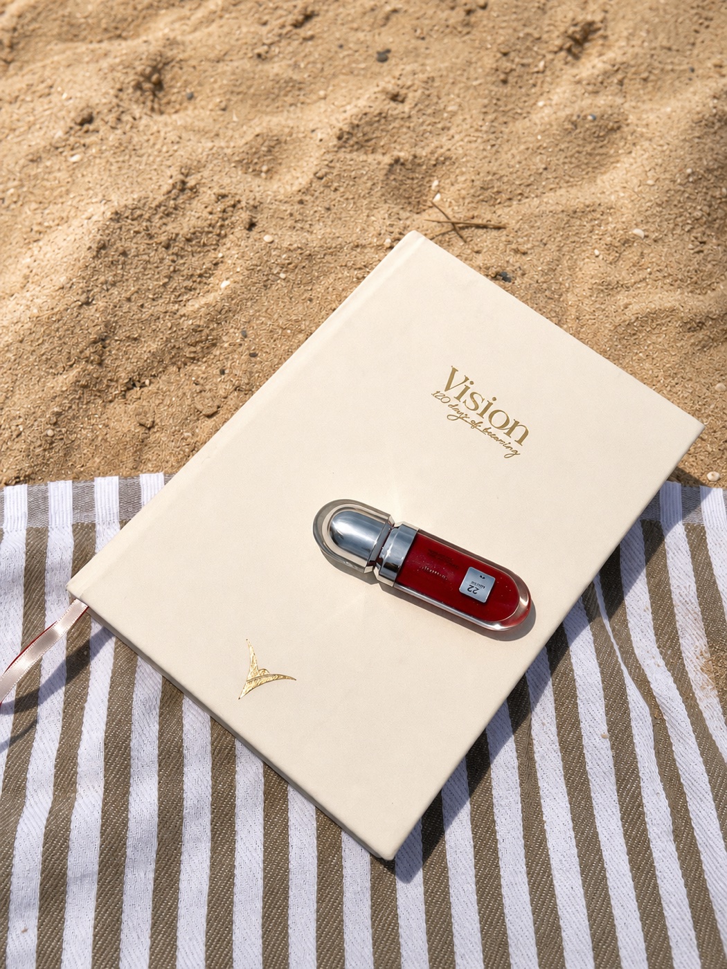 Vision — 120 Days of Becoming planner on a striped beach towel in the sand