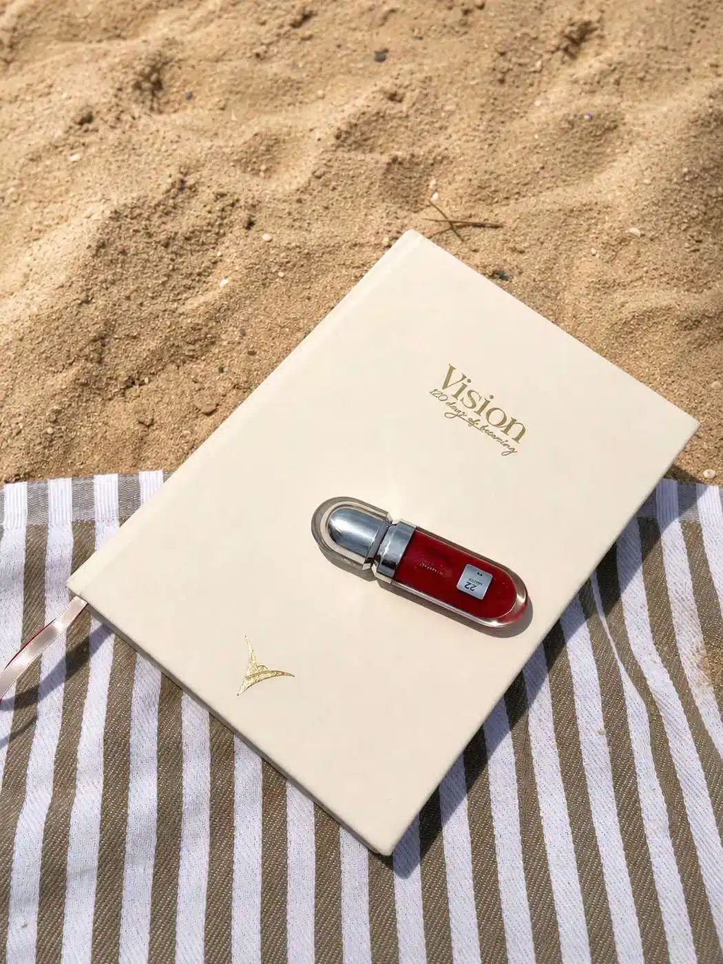 Vision — 120 Days of Becoming planner on a striped beach towel in the sand
